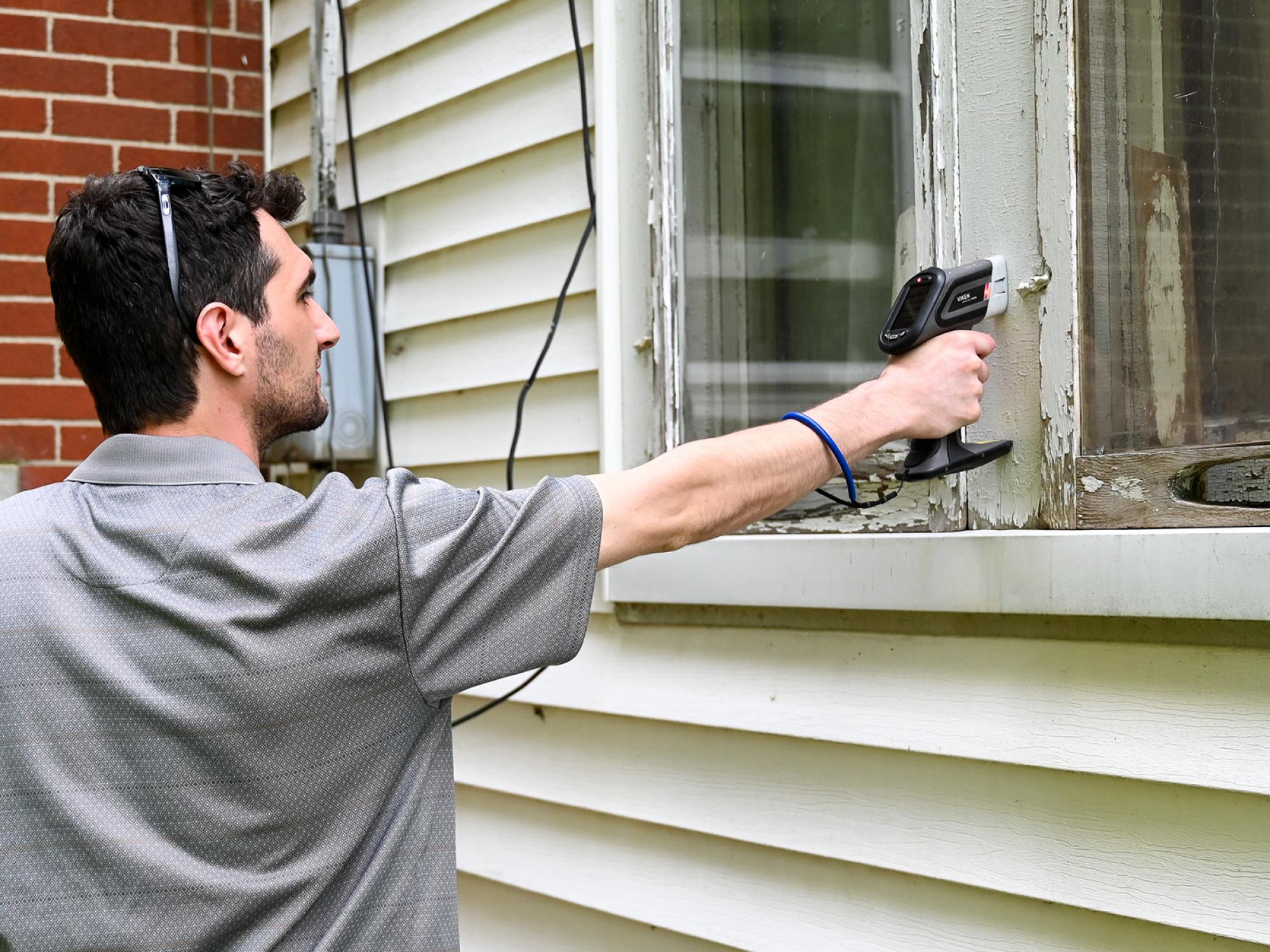 Chautauqua County Health Department staff conducting a lead test on an old windowpane.