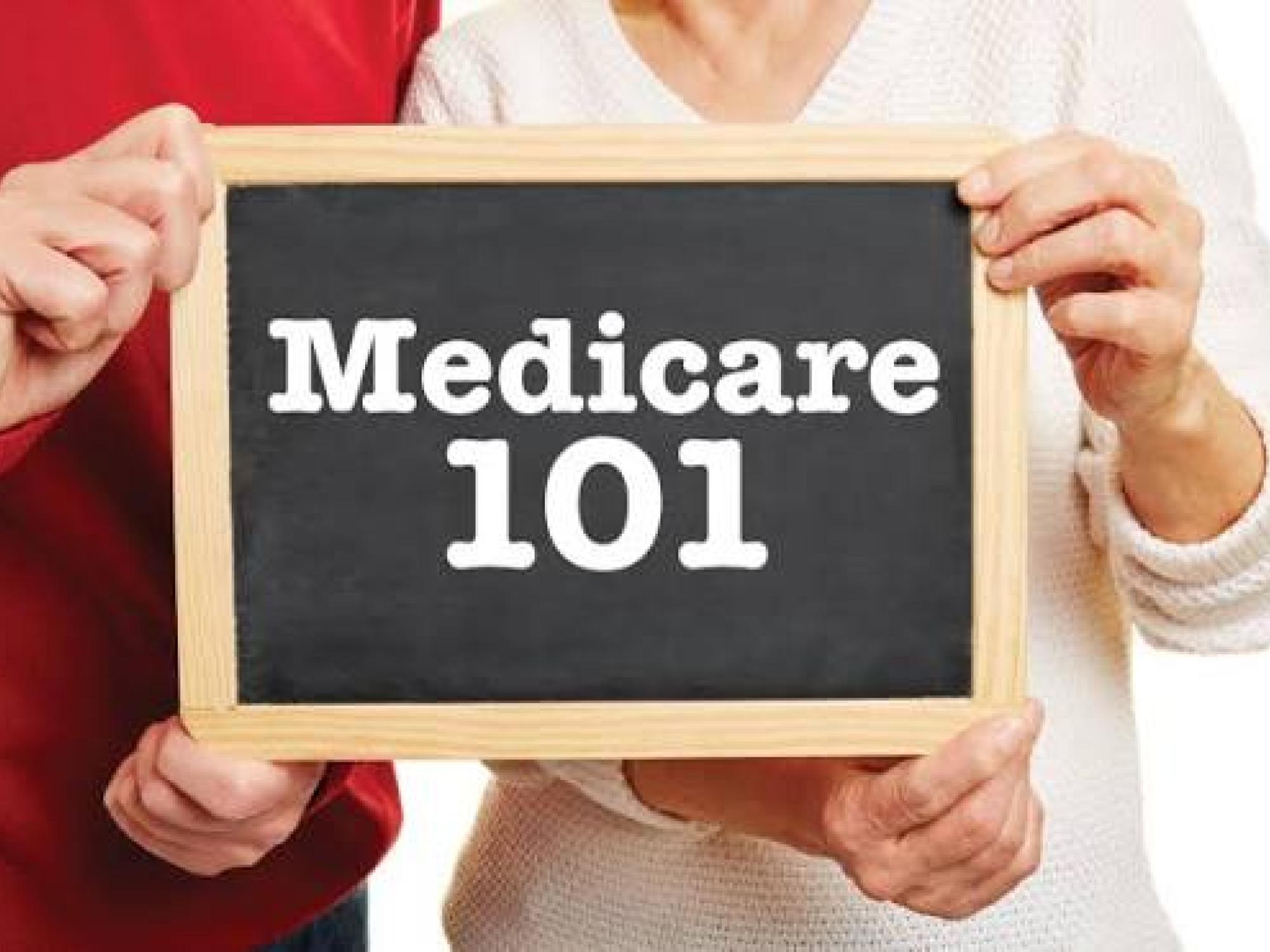 Medicare 101 sign being held by two older adults